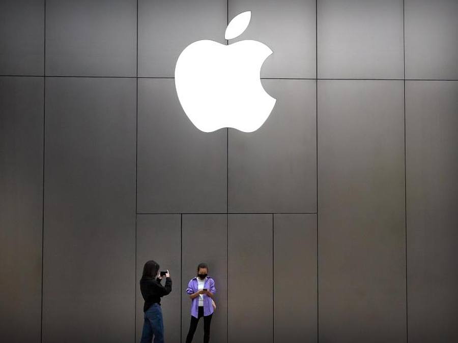 Zwei junge Frauen mit Mundschutz stehen vor einem Apple-Store in Peking. Foto: Mark Schiefelbein/AP/dpa