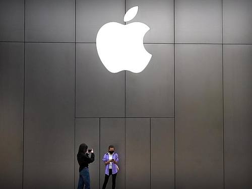 Zwei junge Frauen mit Mundschutz stehen vor einem Apple-Store in Peking. Foto: Mark Schiefelbein/AP/dpa