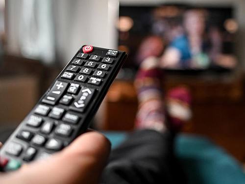Ein junger Mann sitzt mit einer Fernbedienung vor dem Fernseher. Foto: Britta Pedersen/dpa-Zentralbild/dpa