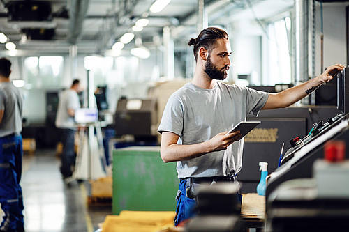 Arbeiter mit Schutzhelm vor CNC-Maschine
