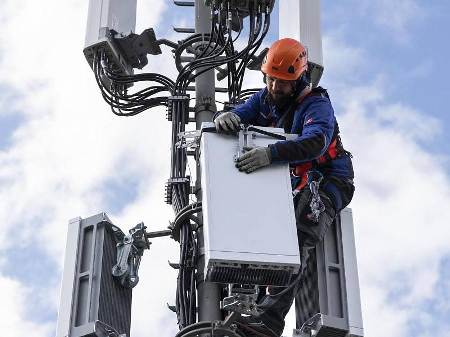 Ein Techniker installiert eine Antenne für das 5G-Funknetz auf einem Hausdach. Foto: Peter Klaunzer/KEYSTONE