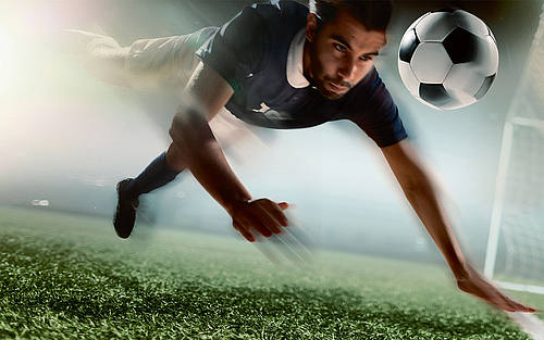 Fußballer hechtet hinter Ball her