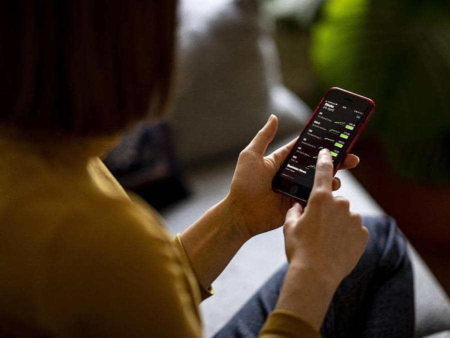 Eine junge Frau beobachtet mit ihrem iPhone die Aktienkurse. Foto: Fabian Sommer/dpa