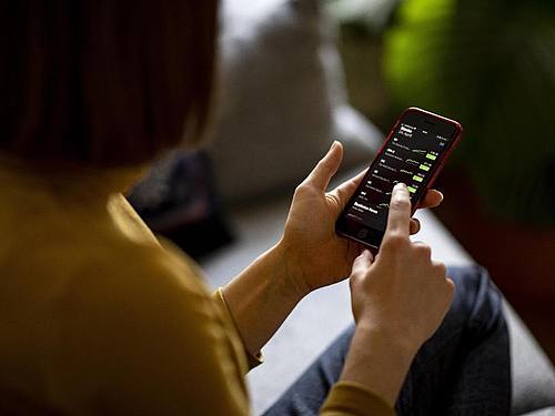 Eine junge Frau beobachtet mit ihrem iPhone die Aktienkurse. Foto: Fabian Sommer/dpa