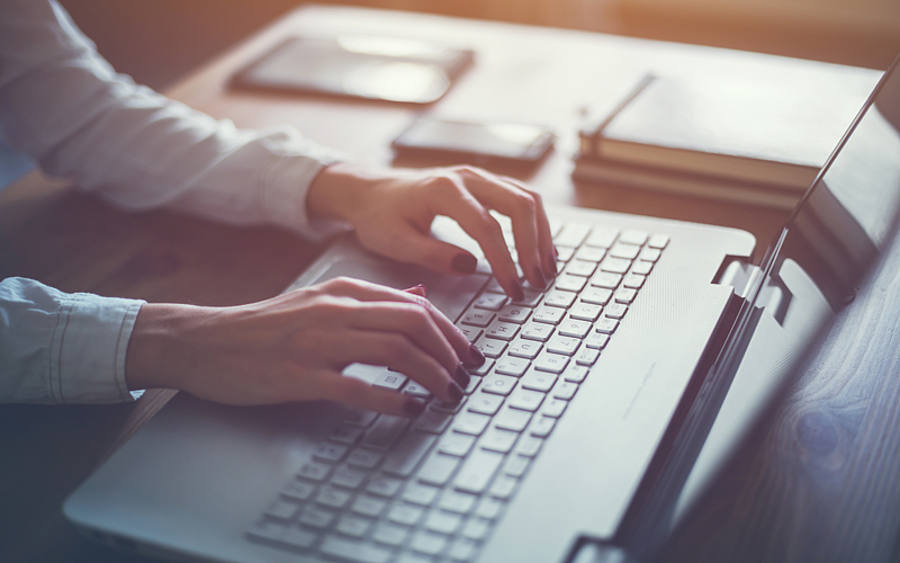 Hände tippen auf eine Notebook-Tastatur