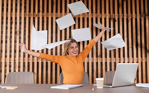 Frau in organgefarbenem Pullover wirft Papier