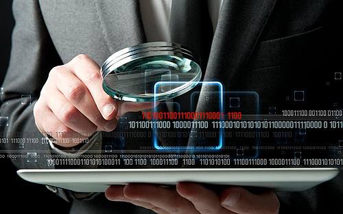 Ein Geschäftsmann sucht per Lupe Daten auf einem Tablet-Computer