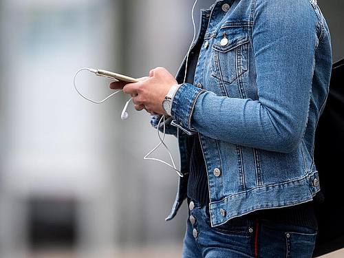 Auch untwegs online: Eine junge Frau an einem Busbahnhof. Foto: Marius Becker/dpa
