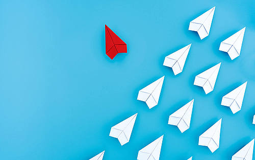 Papierflieger, der eine Flugformation verlässt