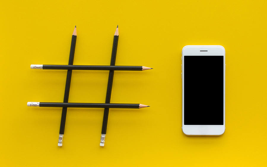 Bleistifte formen einen Hashtag neben einem Smartphone