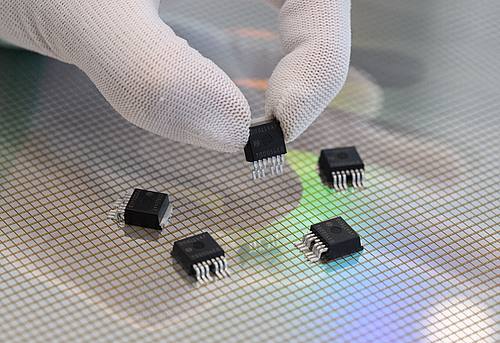 Eine Mitarbeiterin präsentiert in der Halbleiterfabrik von Bosch in Dresden  mikromechanische Sensoren über einem 300-Millimeter-Wafer.