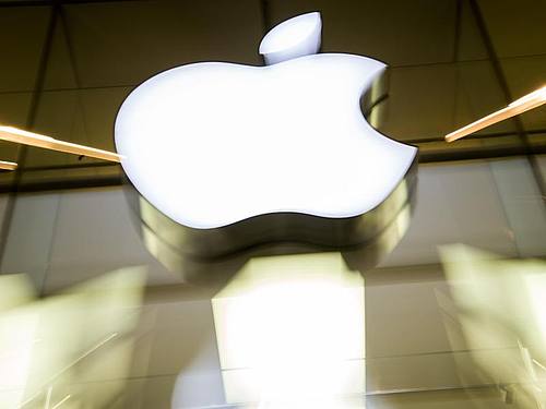 Das Apple-Logo leuchtet an der Fassade des Apple-Store in München. Foto: picture alliance / Peter Kneffel/dpa