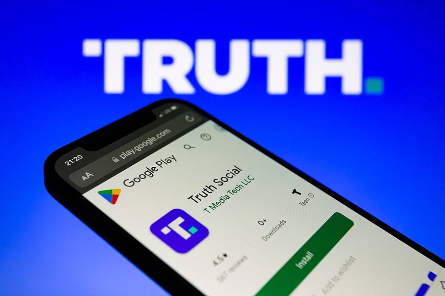Die Truth-App von Trump-Media wird im Google Play Store auf einem Smartphone mit dem Logo im Hintergrund angezeigt.