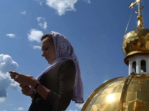 Eine Frau schaut auf dem Dach der orthodoxen Kathedrale von St. Theodor Uschakow in Saransk, Russland, auf ihr Smartphone. Foto: Marcus Brandt/dpa