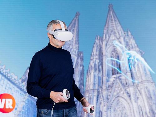 Vodafone-Chef Ametsreiter blickt mit einer Virtual-Reality-Brille auf den digitalen Zwilling des Kölner Doms. Foto: Rolf Vennenbernd/dpa