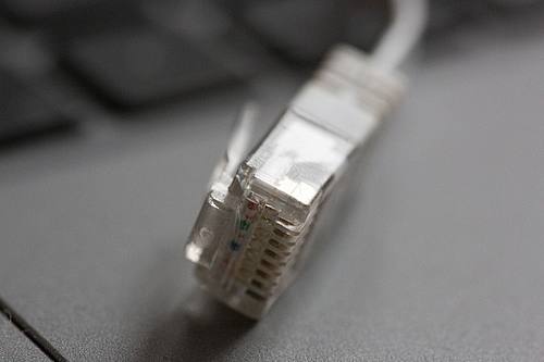 Ein LAN-Kabel liegt auf einem Computerlaptop: Rechtsanspruch auf Versorgung mit Telefon und schnellem Internetzugang.