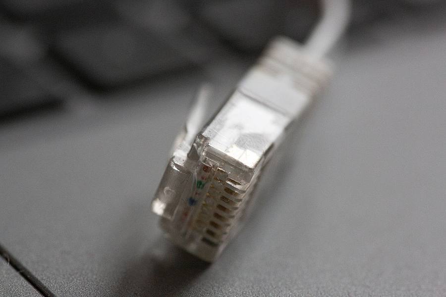 Ein LAN-Kabel liegt auf einem Computerlaptop: Rechtsanspruch auf Versorgung mit Telefon und schnellem Internetzugang.