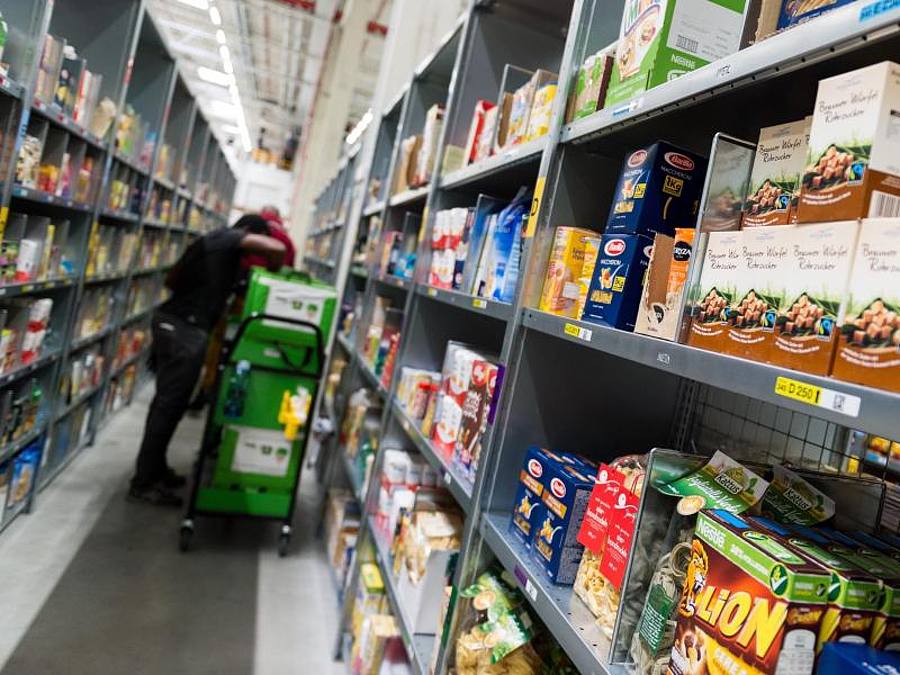 Ein Mitarbeiter des Lebensmittellieferdienstes Amazon Fresh packt bestellte Waren in eine Transporttasche (Archivbild). Foto: picture alliance / Monika Skolimowska/dpa