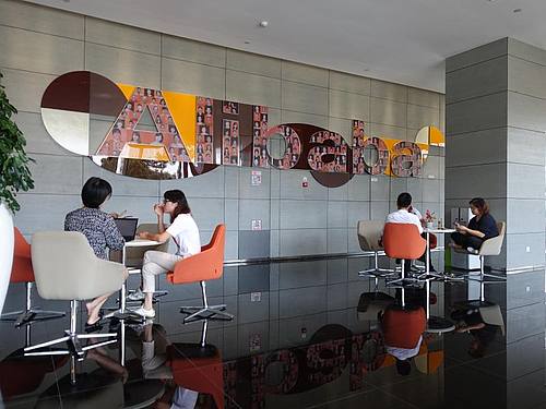 Mitarbeiter sitzen in einem Foyer der Firmenzentrale von Alibaba in Hangzhou. Foto: Andre Klohn/dpa