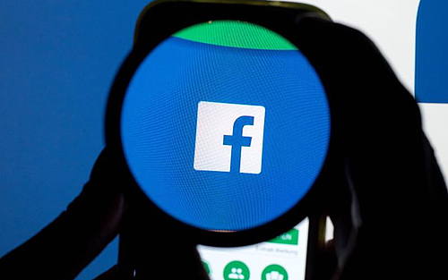 Das Facebook-Logo unter einer Lupe