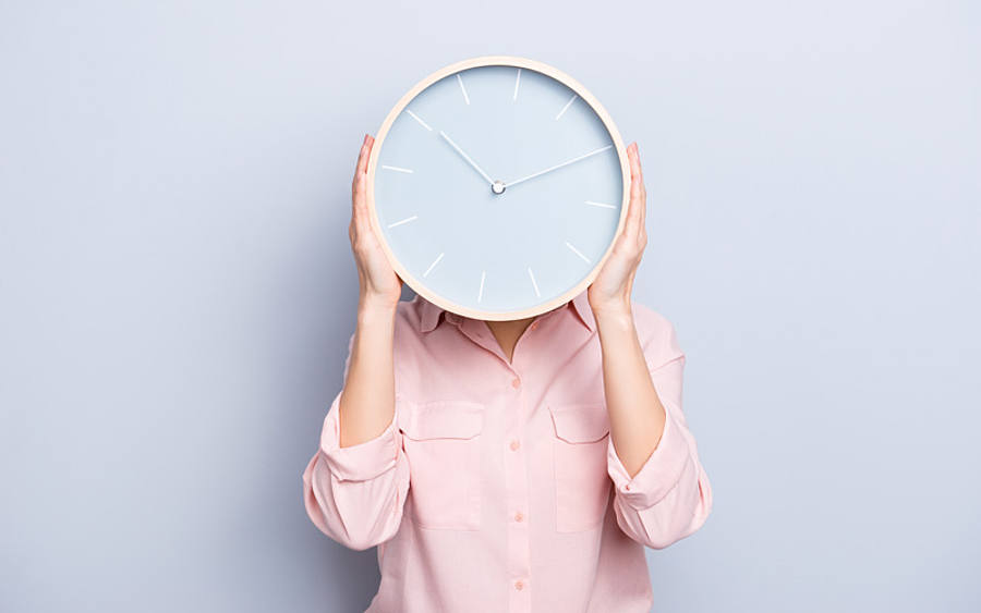 Eine Frau hält sich eine Küchenuhr vor das Gesicht