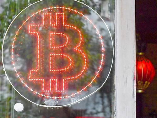 Ein Bitcoin-Logo im Schaufenster einer Kneipe im Kreuzberger Graefekiez in Berlin. Foto: Jens Kalaene/ZB/dpa