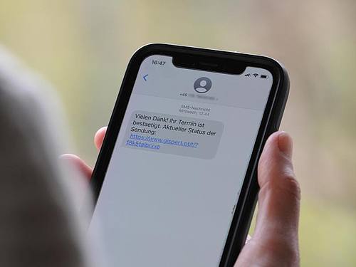 Eine Frau mit einem Smartphone, auf dem eine Betrugs-SMS zu lesen ist. Foto: Wolf von Dewitz/dpa