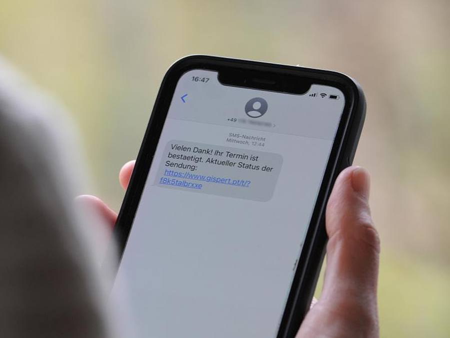 Eine Frau mit einem Smartphone, auf dem eine Betrugs-SMS zu lesen ist. Foto: Wolf von Dewitz/dpa