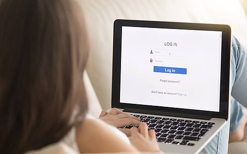 Eine Frau gibt am Laptop ihre Benutzerdaten ein.