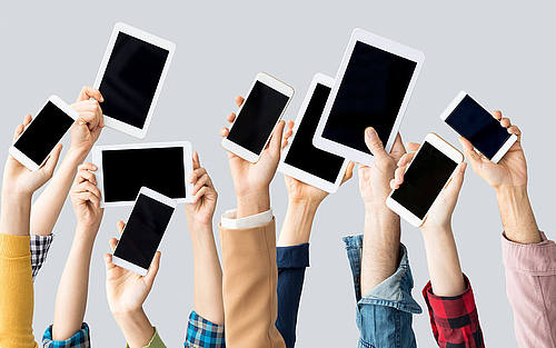 Mitarbeiter halten Smartphones und Tablets in die Luft