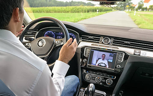 Mann sitzt vor Display in fahrendem Auto