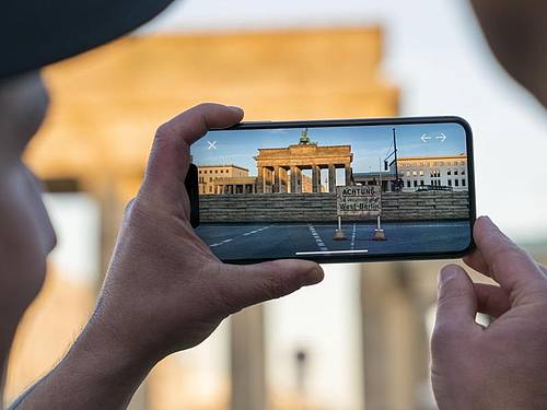 Apple-Chef Tim Cook lässt sich am Brandenburger Tor von Entwickler Peter Kolski das Projekt «MauAR» auf einem Smartphone erklären. Foto: Brooks Kraft/Apple