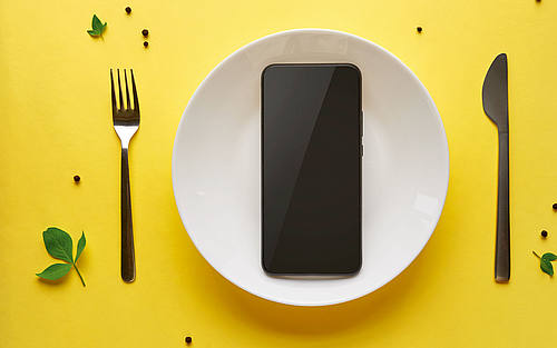 Smartphone auf Teller mit Messer und Gabel