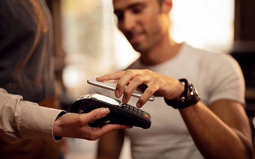 Mann bezahlt kontaktlos mit Smartphone
