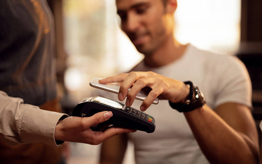 Mann bezahlt kontaktlos mit Smartphone