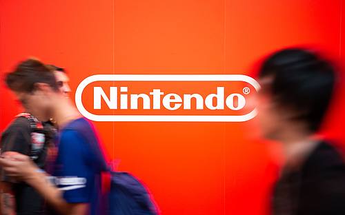 Besucher auf der Gamescom laufen an dem Nintendo-Logo vorbei.