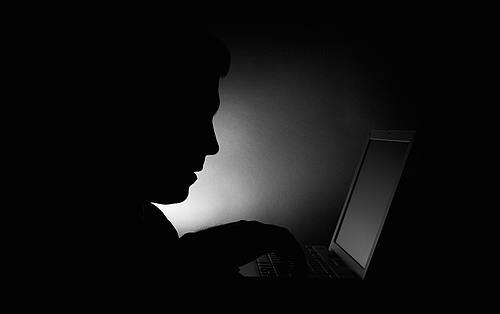 Dunkle Silhouette einer Person vor einem Laptop