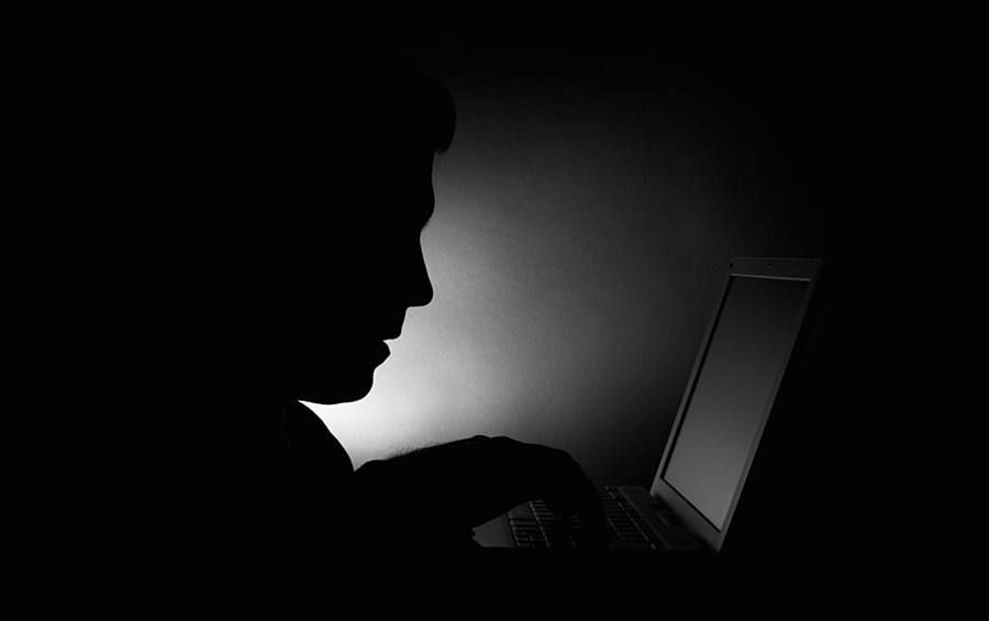 Dunkle Silhouette einer Person vor einem Laptop