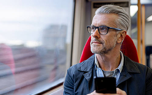 Mann in Zug mit Smartphone