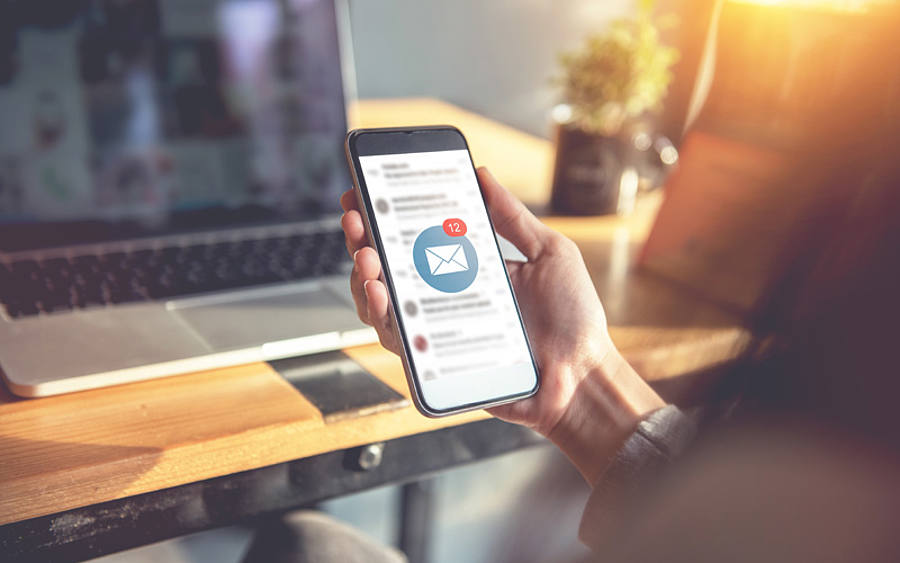 Eine Büroangestellte ruft per Smartphone ihre E-Mails ab