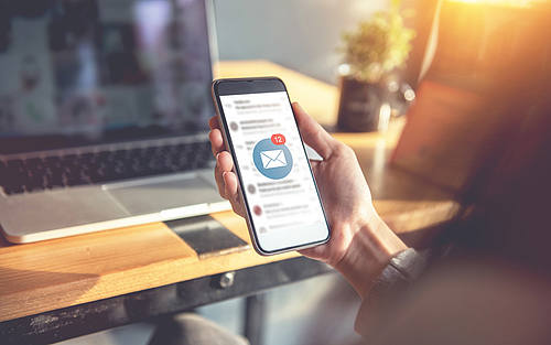Eine Büroangestellte ruft per Smartphone ihre E-Mails ab