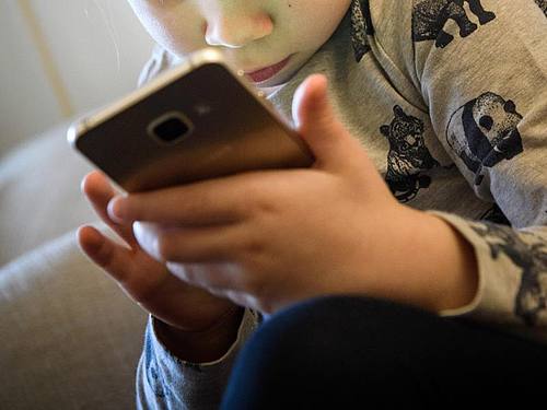 Ein kleines Mädchen spielt auf einem Smartphone. Foto: Hans-Jürgen Wiedl