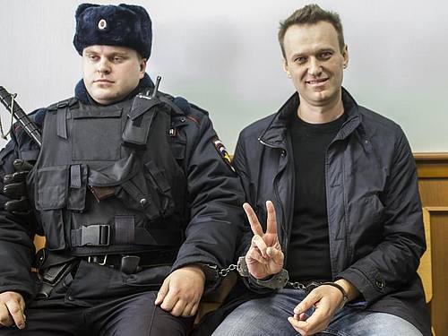 Kremlgegner Alexej Nawalny (r) zeigt ein Victory-Zeichen, während er neben einem Sicherheitsbeamten im Gericht sitzt (Archivbild). Foto: Evgeny Feldman/AP/dpa