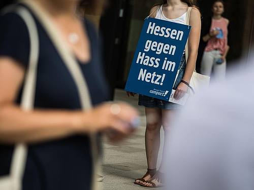 Eine Aktivistin der Nichtregierungsorganisation Campact steht mit einem Plakat mit der Aufschrift "Hessen gegen Hass im Netz" am Eingang zum Landesparteitag von Bündnis 90/Die Grünen in Hessen, Foto: Frank Rumpenhorst
