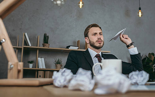 Mann wirft Papierflieger im Büro