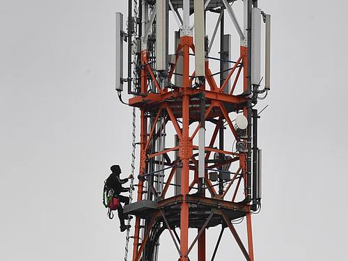 Ein Techniker klettert an einem Funkmast neben Mobilfunkantennen für den Mobilfunkstandard 5G. Foto: Stefan Sauer/zb/dpa