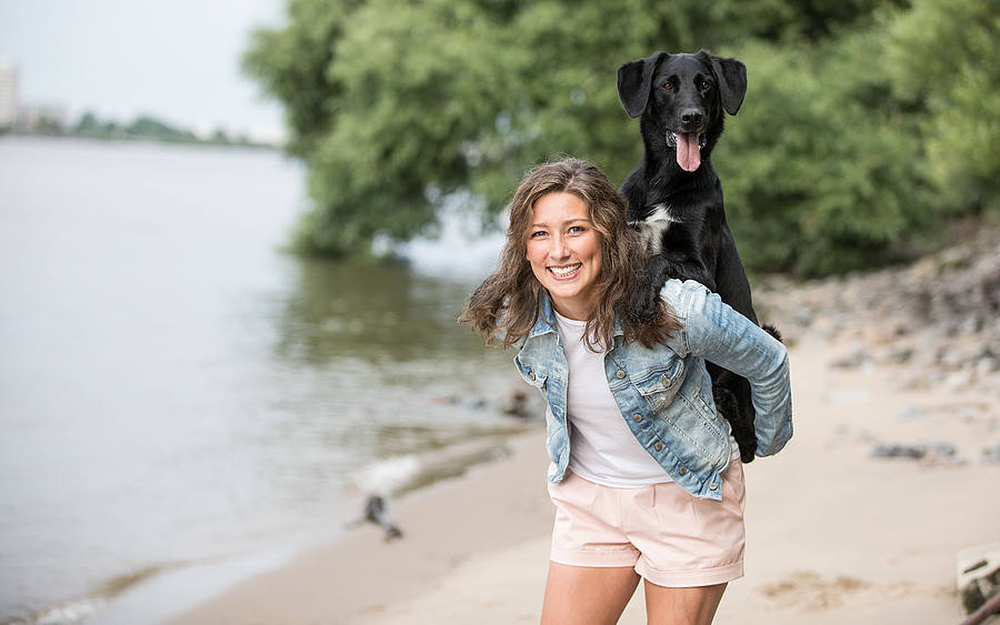 Mädchen spielt mit Hund an einem Fluss