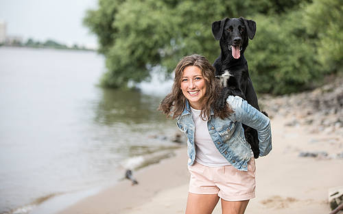 Mädchen spielt mit Hund an einem Fluss