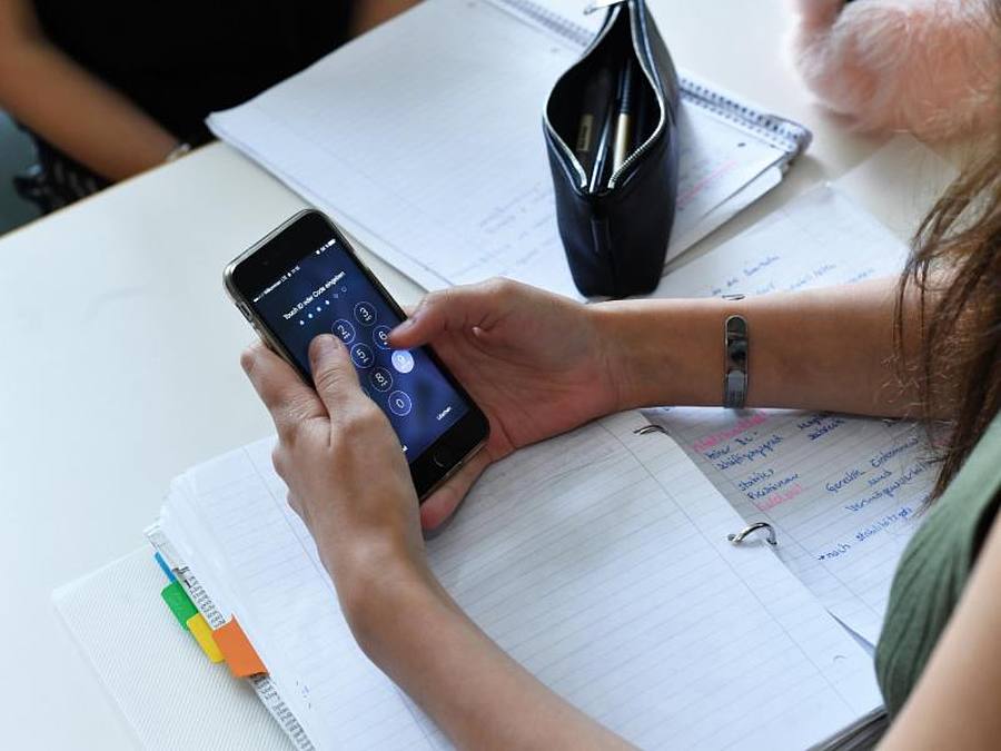 Eine Schülerin hält im Unterricht ein Handy in den Händen. Foto: Jens Kalaene/Illustration