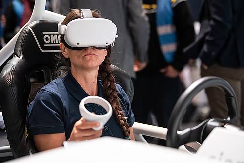 Eine Frau sitzt am Stand der Firma Siemens im vollelektrischen Fahrzeug SimRod.